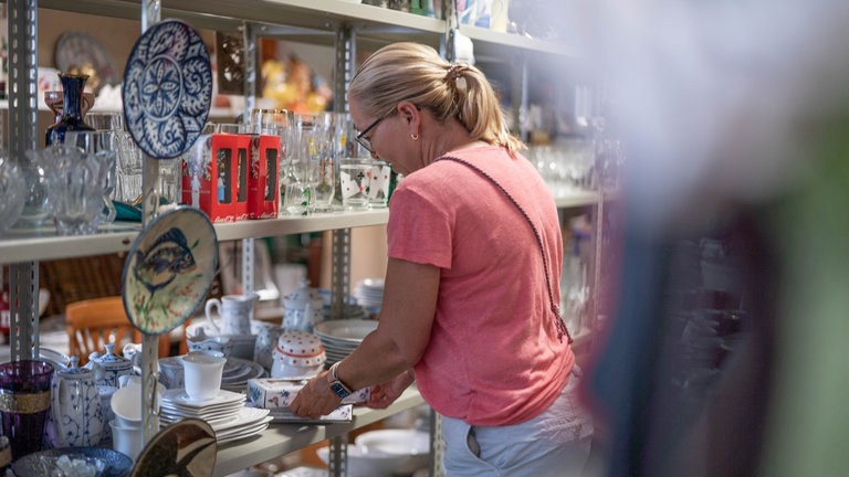 Silke Schulz räumt im „Kaufhaus der Wiederkehr“ in Worms Waren in die Regale. Dort werden Secondhandartikel preiswert verkauft, um einen nachhaltigen Konsum zu ermöglichen und Müll zu reduzieren.