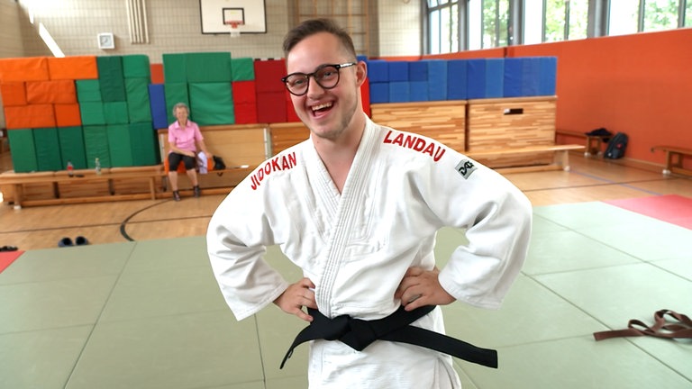 Sich freuender junger Mann mit Judo-Anzug und schwarzem Gürtel.