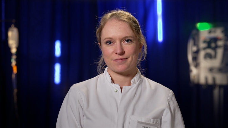 Jennifer ist Assistenzärztin in der Orthopädie und Unfallchirurgie. Sie sitzt vor einem blauen Hintergrund und schaut in die Kamera. 