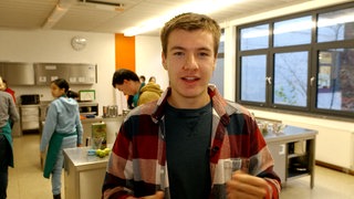 Schüler in Klassenzimmer schaut in die Kamera