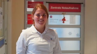 Eine blonde, junge Frau lächelt in die Kamera.