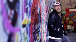 René aus Kaiserslautern steht vor Graffiti Wand
