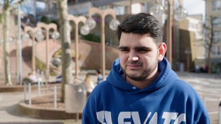Junger Mann auf einem Platz in Interviewsituation.