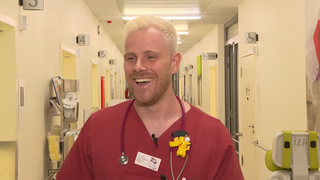 Aaron, angehender Kinderarzt, mit seinem Kittel in einem Krankenhausflur. 