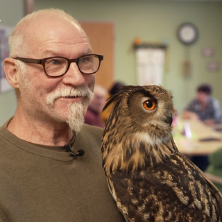Ein Mann mit Uhu lächelt