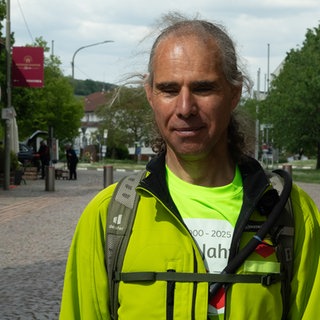 Ein Mann mit gelber Jacke hat die Augen geschlossen. Ralf ist blind und wandert seit 20 Jahren ohne Sehkraft.