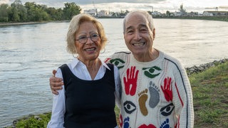 Ein Mann hat seinen Arm um eine Frau gelegt, das Paar steht am Rhein und lacht in die Kamera. Für ihre interkulturelle Beziehung wurden Heidi und der italienische Gastarbeiter Luigi in den 1960er Jahren angefeindet.