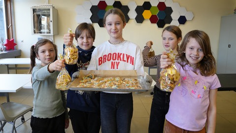 Fünf Kinder halten selbstgebackene Plätzchen in die Kamera.
