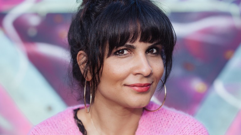 Frau in pinkfarbenen Pullover, die Haare zu einem Dutt zusammengebunden. 