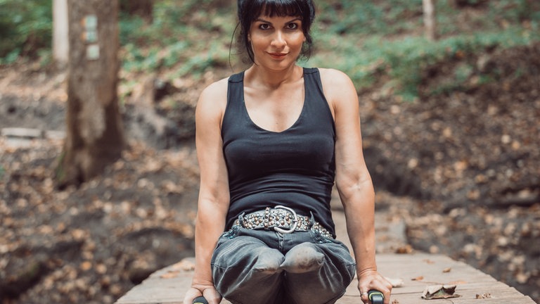 Frau ohne Beine läuft auf ihren Händen durch den Wald.