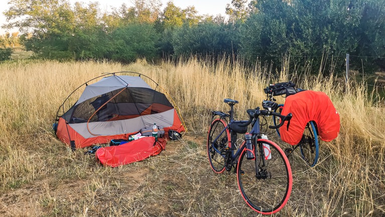Mitten auf einer Wiese ein Zelt mit zwei Fahrrädern. Ein Camp zum Übernachten.