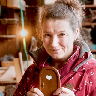 Frau mittleren Alters, mit kleiner Wichteltür in ihrer weihnachtlichen Werkstatt