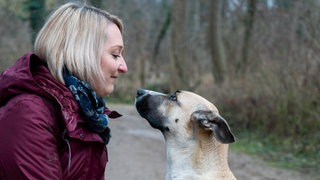 Weiblich gelesener Mensch mit Hund im Wald