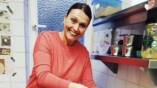 Frau in einer Restaurantküche am Mixer.