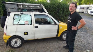 Junger Mann mit seinem Kleinwagen-Camper