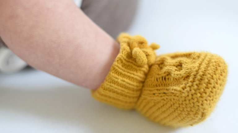 Ein Teil eines Beines und ein gelber Babyschuh sind zu sehen.