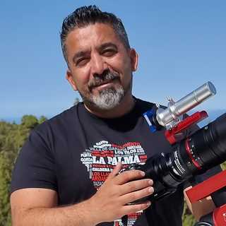 Mann auf Berg mit Kamera auf Stativ zum Sternefotografieren