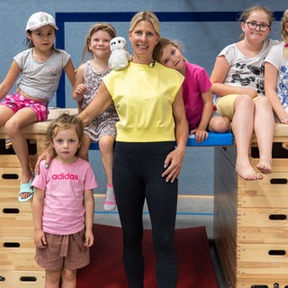 Blonde Frau lächelt in die Kamera, gemeinsam mit Kindern.