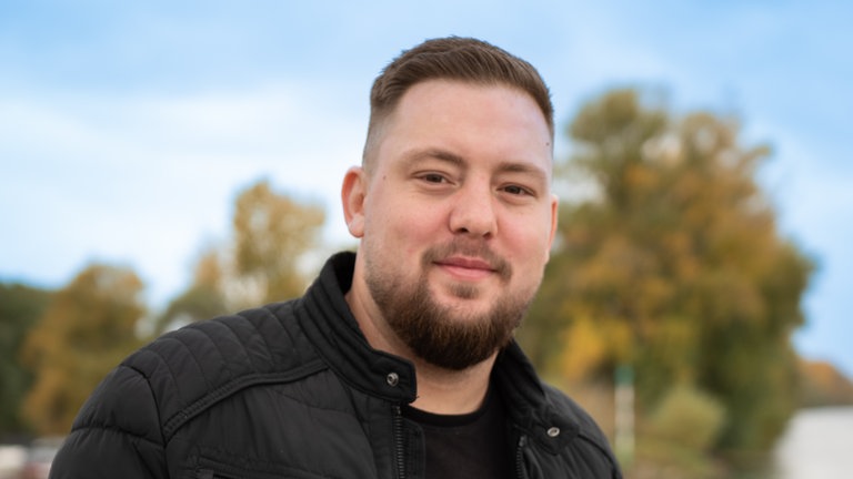 Jens, 30 Jahre alt, steht am Rhein.