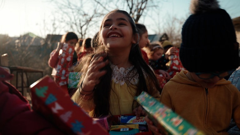 Ein lachendes Kind mit langen braunen Haaren.
