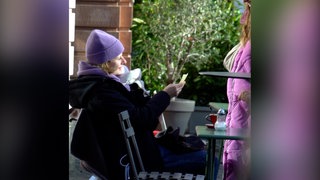 Eine junge Mutter sitzt draußen in einem Cafe.