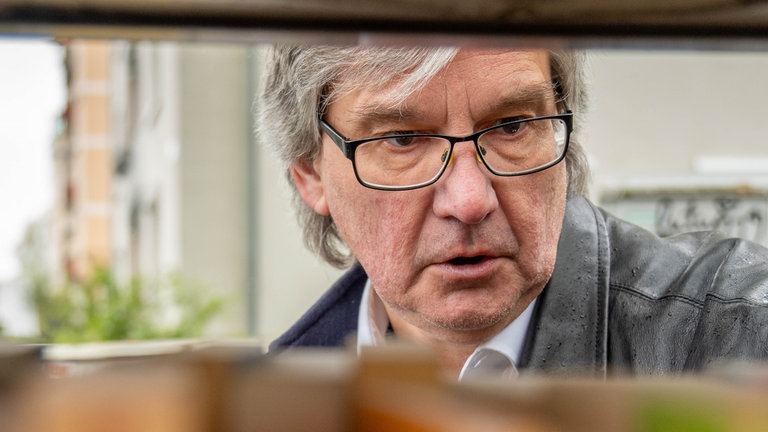 Ein Mann schmökert in einem Bücherkasten. Felix ist leidenschaftlicher Büchersammler und besucht jeden Tag die „Offene Bibliothek“ in der Mainzer Neustadt.