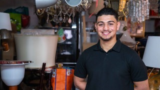 Junger Mann, der im Antiquitätenladen steht