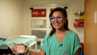 Junge Frau lachend in OP-Kittel.