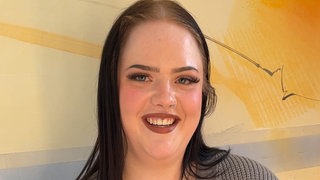 Eine junge Frau sieht lächelnd in die Kamera.