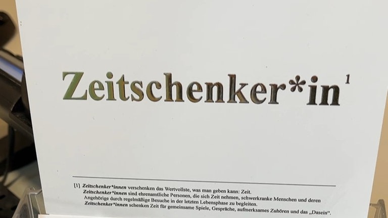 Ein ausgedrucktes Schild, auf dem „Zeitschenker*in“ steht.