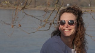 Junge Frau mit Sonnenbrille vor dem Rhein