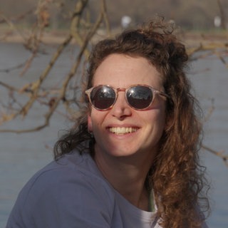 Junge Frau mit Sonnenbrille vor dem Rhein