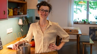 Junge Frau in der Küche neben einem Kochtopf