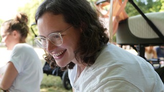 Die junge Mama Conny sitzt auf einer Picknickdecke und lächelt.