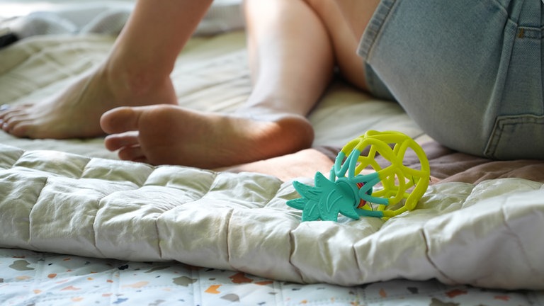 Leonie hält ihre Tochter und lächelt sie an.