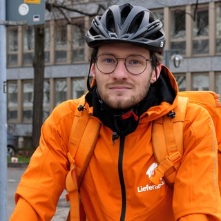 Fahrradkurier in orangener Jacke vom Lieferdienst Lieferando