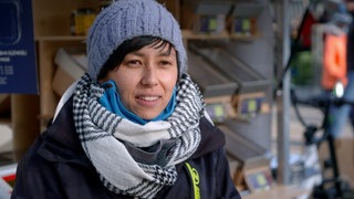 Verkäuferin steht mit Wollmütze und Schal auf dem Ludwigsburger Wochenmarkt