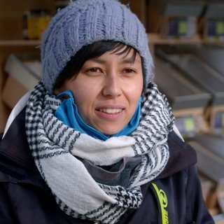 Verkäuferin steht mit Wollmütze und Schal auf dem Ludwigsburger Wochenmarkt