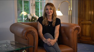 Monika sitzt auf einem Sessel im Wohnzimmer