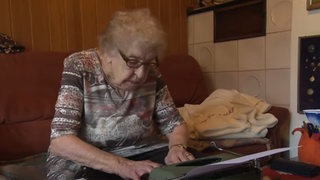 Alte Frau sitzt gebeugt über Schreibmaschine