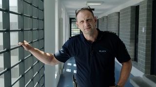 Mann im Gefängnis hält sich an Gitterstäben fest