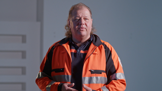 Rettungssanitäter in orangener Kleidung schaut in Kamera