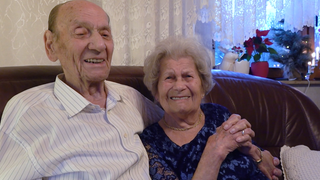 Ein Liebespasst sitzt auf dem Sofa. Sie feiern gemeinsam 75 Jahre Ehe.