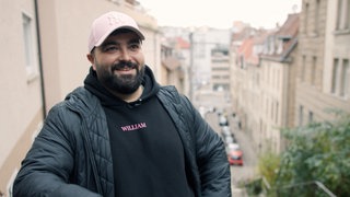 Serdar Karibik - Ein Mann steht in Stuttgart. Viele Häuser im Hintergrund