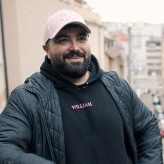 Serdar Karibik - Ein Mann steht in Stuttgart. Viele Häuser im Hintergrund