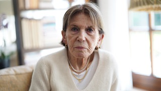 Ruth ist 95 Jahre alt und Zeitzeugin des Zweiten Weltkriegs. SWR Heimat hat sie zu Hause besucht und sie erzählt von ihren Erlebnissen während dem Krieg. Sie sitzt auf dem Sofa in ihrem Wohnzimmer.