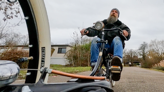 Michael fährt auf einem seiner selbstgebauten Fahrräder, durch einen Park.
