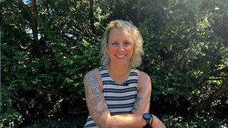 Juliane sitzt während eines Spaziergangs ihrer Women Walk and Talk Gruppe auf einer Bank im Grünen am Killesberg in Stuttgart.