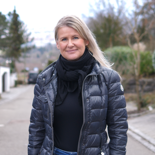 Migräne-Patientin Simone ist eine blonde Frau Anfang 50, sie schaut in die Kamera und steht auf einem Weg.