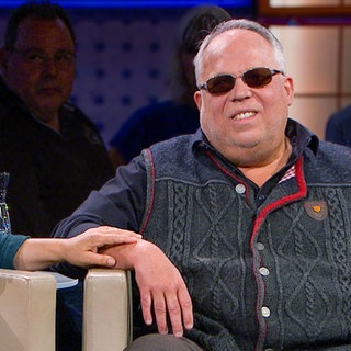 Peter ist aufgrund des Usher-Syndroms taubblind und kann die Welt nur über Berührungen wahrnehmen. Seine Frau Margherita und er kommunizieren über Berührungen und Gebärden. Margherita trägt einen grünen Oberteil und einen grünen Schal, neben ihr sitzt Peter. Margherita legt ihre Hand auf Peters Arm.